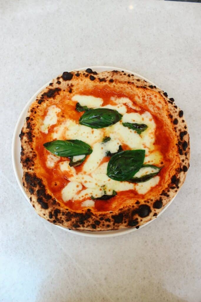 Top-down view of freshly baked Neapolitan Margherita pizza with basil and cheese.