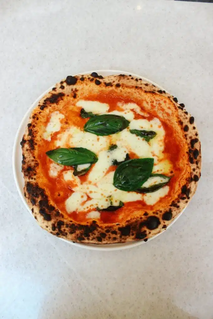 Recette de pesto aux fanes de radis Top-down view of freshly baked Neapolitan Margherita pizza with basil and cheese.